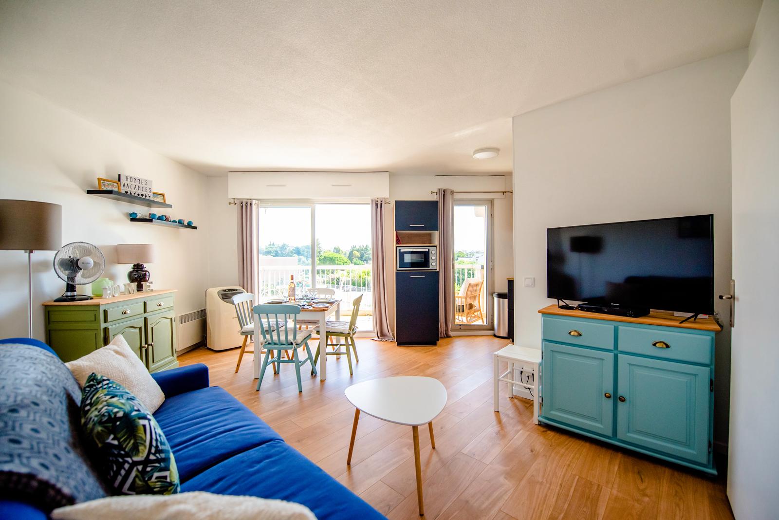 Dans cet appartement du bord de mer, destiné à la location de vacances, nous avons repensé la décoration afin de créer une atmosphère plus chaleureuse et accueillante.
Nous avons remplacé l’ancien carrelage un peu vieillot par un joli parquet aux teintes chaudes.
Les murs et le plafond ont été repeints en blanc chaud afin d’éclaircir la pièce, qui est déjà baignée de lumière.
Certains meubles comme la table à manger, les chaises et le buffet, ont été conservés afin de réduire le budget mobilier, mais ils ont été poncés et repeints afin de leur donner une nouvelle jeunesse. En revanche, le canapé et la table basse ont été achetés neufs.
Un peu de décoration a été ajoutée afin d’ajouter un aspect cocooning au lieu.